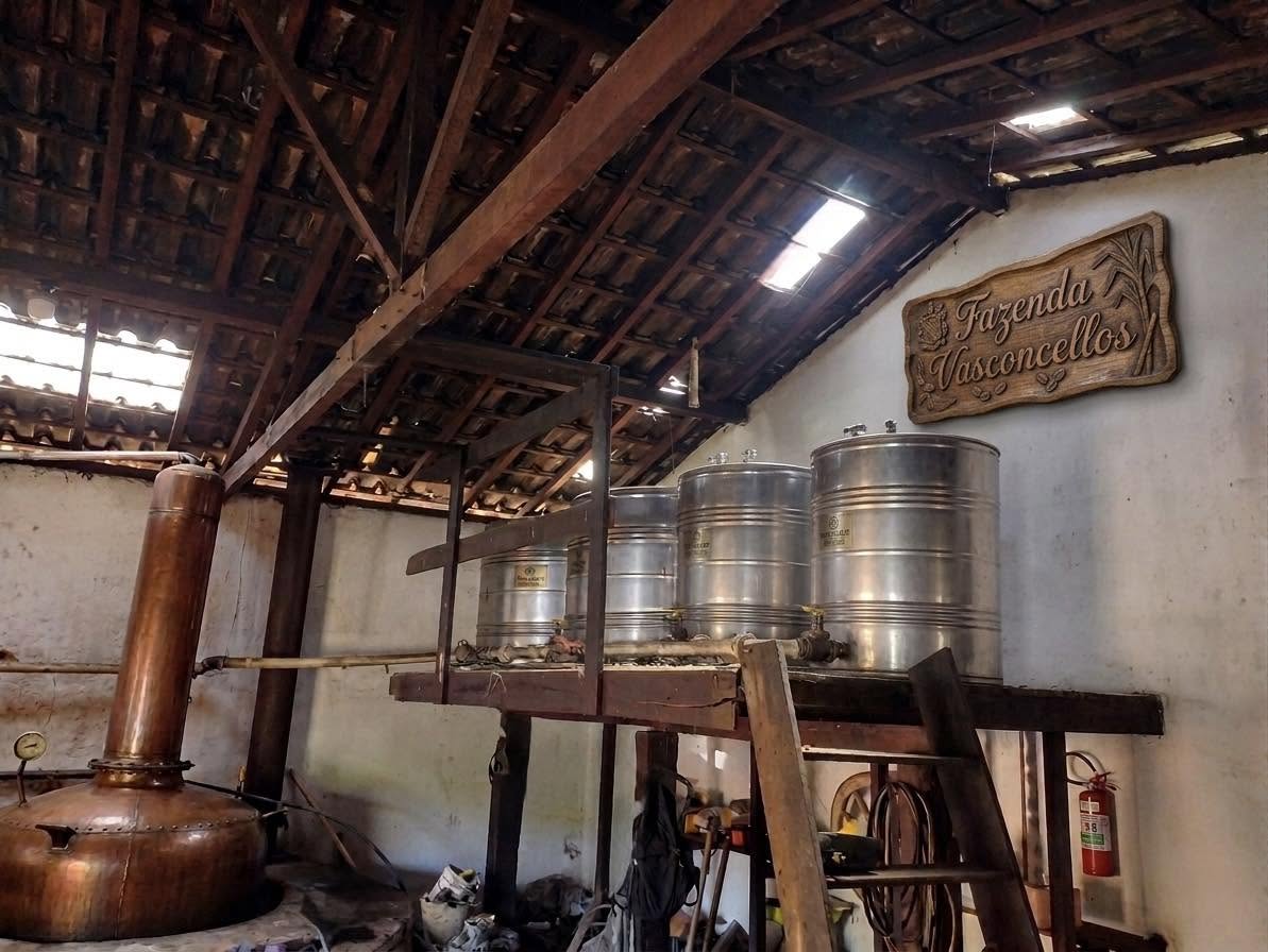 Galpão do alambique com tanques de inox e placa da Fazenda Vasconcellos