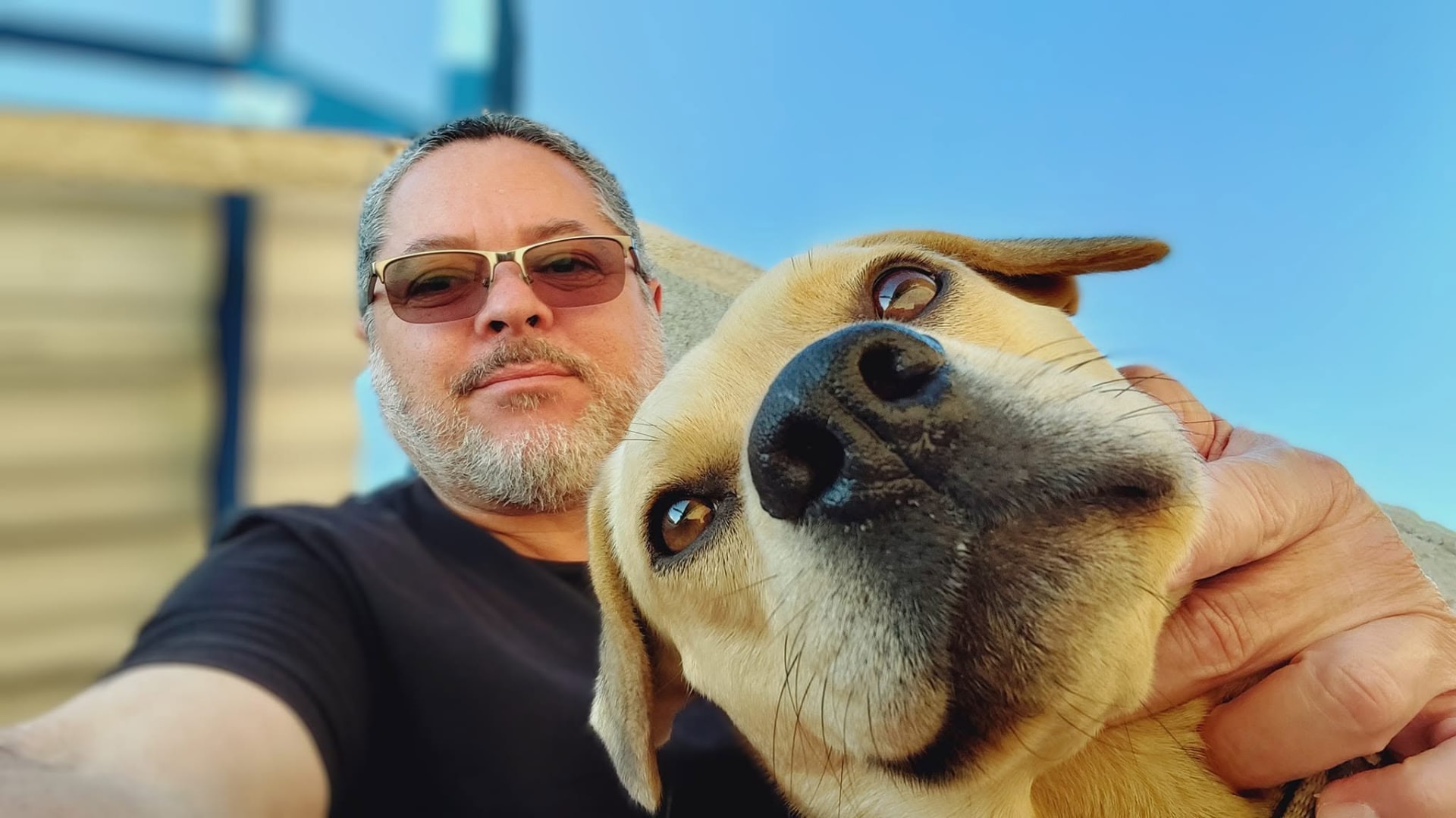 Homem sorrindo ao lado do cachorro da fazenda sob o céu azul