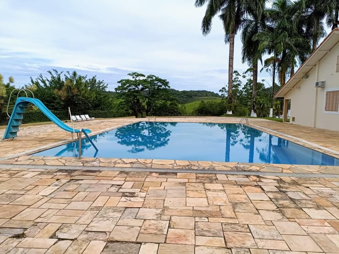 Piscina da sede da Fazenda Vasconcellos com escorrega e vista para as montanhas