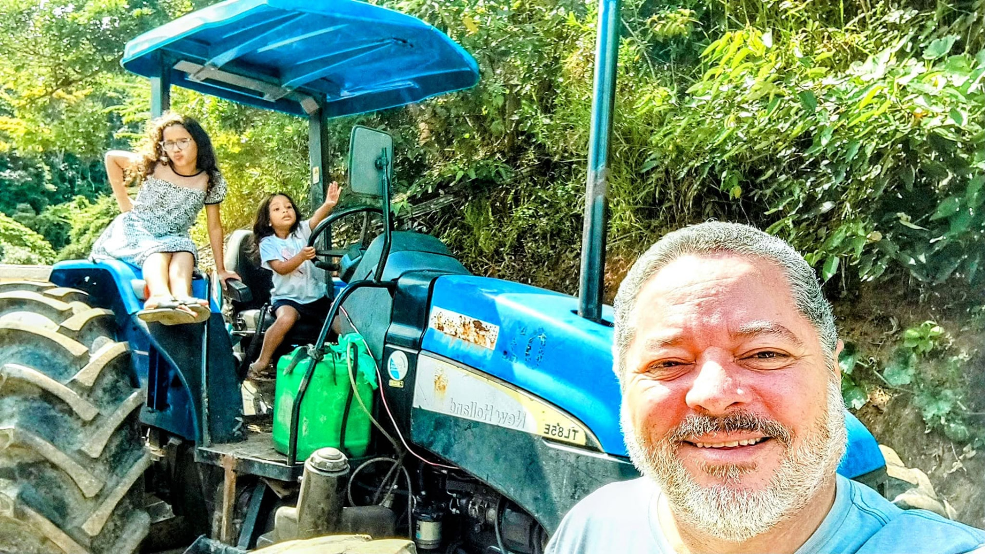 Pai e filhas sorrindo no trator da Fazenda Vasconcellos